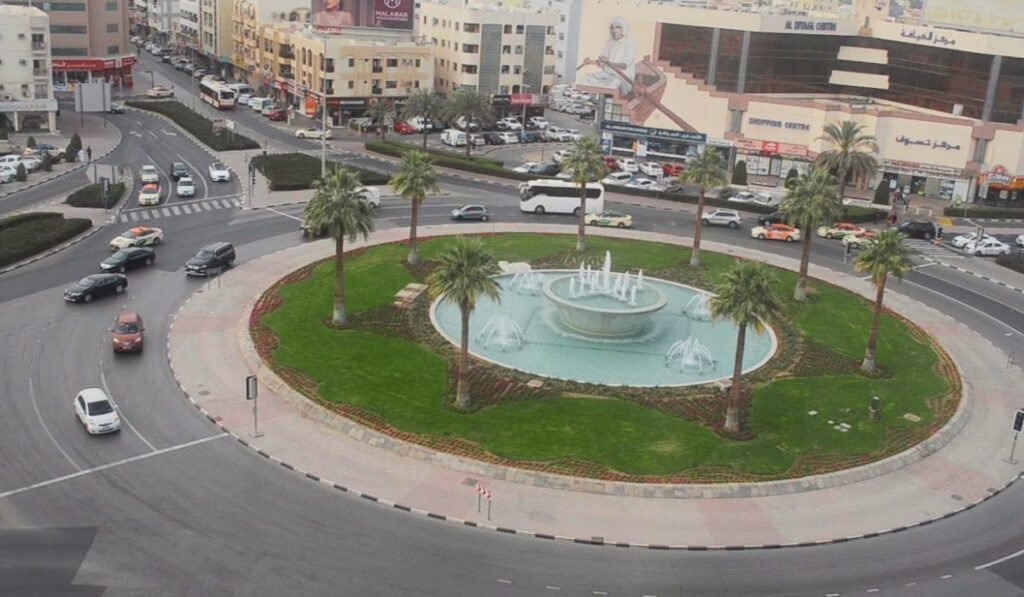 Busy Satwa Roundabout in Dubai with city traffic, a green center, and high-rise buildings.