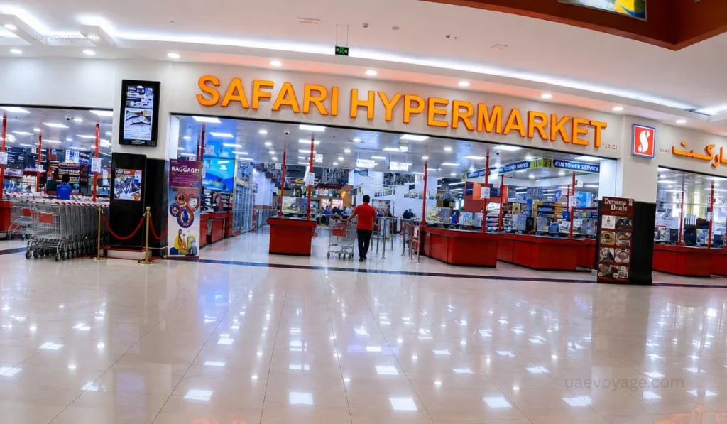 Safari Hypermarket entrance inside Safari Mall Sharjah with shopping carts, bright store sign, red counters and a man in red shirt entering.